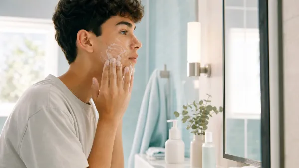 Teenager calmly using a gentle cleanser at a bright bathroom mirror